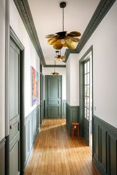 an empty hallway with wooden floors and green painted walls, along with two large ceiling fans