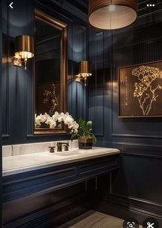 a bathroom with blue walls and white flowers in the sink area, along with two framed pictures on the wall