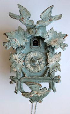 an old clock with birds and leaves on it's face is hanging from the wall