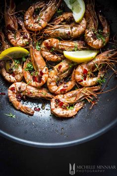 cooked shrimp with lemon wedges and parsley in a wok on a table