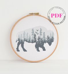 a cross stitch pattern of a bear in the woods with pine trees on it's back