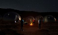 several people standing around a campfire in the middle of an open field at night