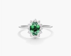 18K White Gold Oval Halo Emerald and Diamond Ring (7.0x5.0mm). Celebrate a classic look with this stunning ring featuring an oval emerald surrounded by a halo of glistening diamonds. The unique prong setting of the diamond halo lends a vintage feel to this chic piece that will instantly upgrade any look. Oval Halo Ring With May Birthstone, Oval Halo Emerald Ring For May Birthstone, Elegant Oval Cabochon Emerald Ring With Halo Setting, Elegant Emerald Ring With Oval Cabochon Halo Setting, Elegant Oval Emerald Ring With Halo Setting, Formal Oval Emerald Ring With Halo, Gia Certified Oval Emerald Halo Ring, Elegant Green Oval Halo Ring, Elegant Oval Halo Ring For May Birthstone