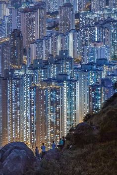 people are standing on the edge of a cliff at night in hong kong, china