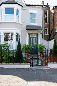 a white house with a black gate and flowers