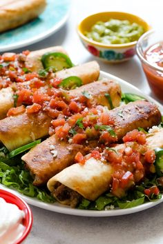 a white plate topped with lots of food next to bowls of sauce and condiments