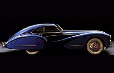 an old blue car sitting on top of a wooden table in front of a black background