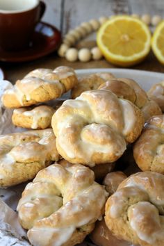 glazed donuts with icing on a plate next to some coffee and lemons