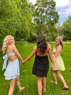 three young women holding hands in the grass