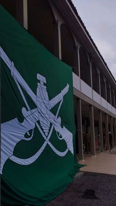 a green flag with a white bow and arrow on it in front of a building