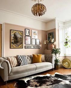 a living room filled with furniture and pictures hanging on the wall next to a window