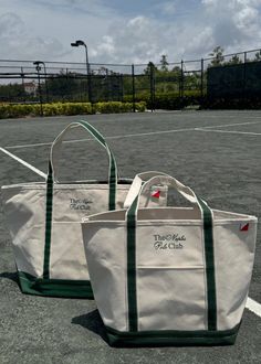 two white bags sitting on top of a tennis court