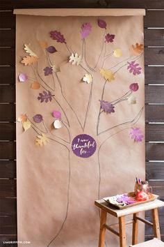 a paper tree with purple and gold leaves on it is next to a small table