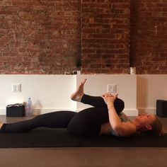 a woman is doing yoga on a mat in front of a brick wall and floor