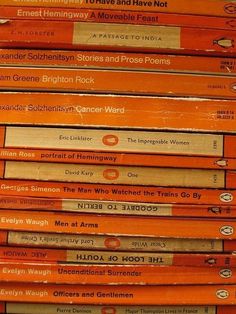 a stack of orange books sitting next to each other on top of a wooden table