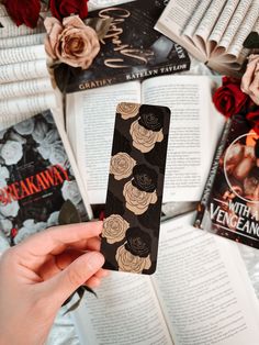 a person holding an iphone case with roses on it next to books and flowers in the background