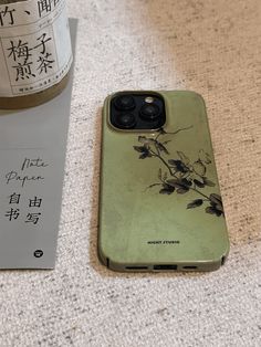 an iphone case sitting on the ground next to a wine bottle and some chinese writing