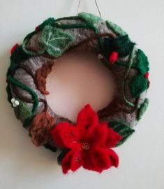 a felt wreath with poinsettis hanging from the side on a white wall