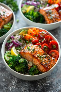 three bowls filled with salmon, broccoli, tomatoes and other veggies