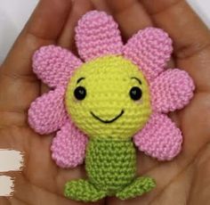 a hand holding a small crocheted toy with a flower on it