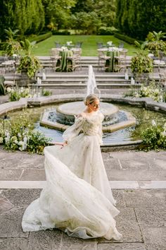 a woman in a wedding dress standing next to a fountain