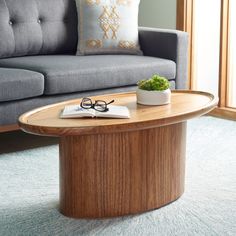 a coffee table with a book and glasses on it next to a couch in a living room