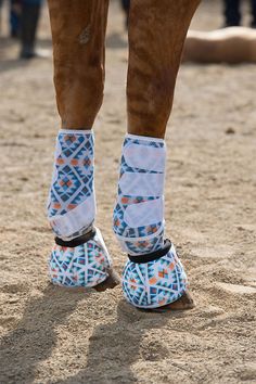 the legs and feet of a horse wearing socks with designs on them, standing in sand