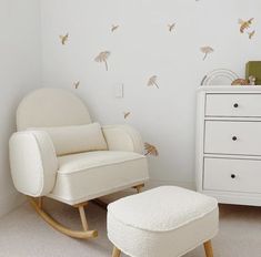 a white rocking chair and foot stool in a child's room