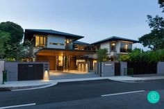 a large modern house with an entrance and gated driveway at dusk, in the evening