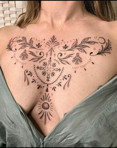 a woman's chest with an intricate tattoo design on her left shoulder and right breast