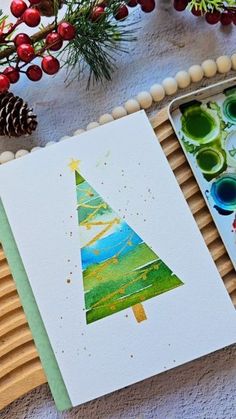 two christmas cards on a tray next to pine cones