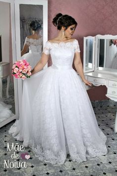 a woman in a white wedding dress is looking at herself in the mirror and holding a bouquet