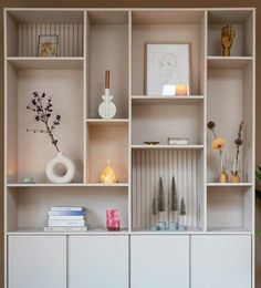 a white shelf filled with lots of books and vases on top of each other