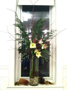 a vase filled with flowers sitting on top of a window sill next to pine cones