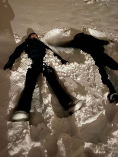 two people laying in the snow on their back