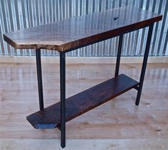 a wooden table sitting on top of a hard wood floor next to a metal wall