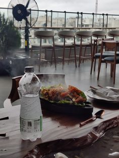 a bottle of water sitting on top of a table next to a plate of food