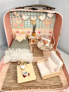 an open suitcase filled with furniture on top of a white table and floor next to a wall