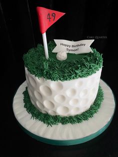 a golf themed birthday cake with green grass and white frosting on a black background