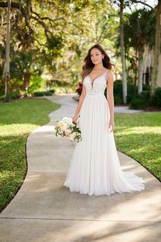 a woman in a white wedding dress is standing on the sidewalk and holding a bouquet