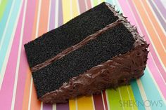 a piece of chocolate cake sitting on top of a colorful table cloth with stripes in the background