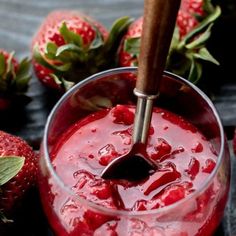 strawberry jam in a glass bowl with a wooden spoon and fresh strawberries around it