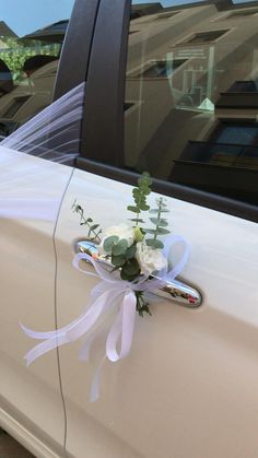 a bouquet of flowers is tied to the side of a white car with ribbons on it