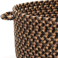 a brown and black woven basket on a white background with the handle down to it's side