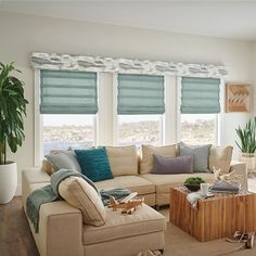 a living room filled with furniture and windows covered in blue roman blind shades on top of them