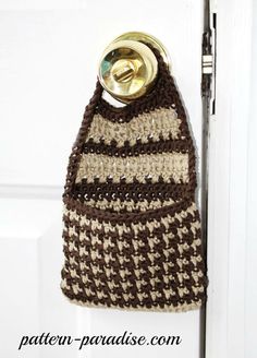 a crocheted purse hanging on a door handle with a bottle opener attached to it