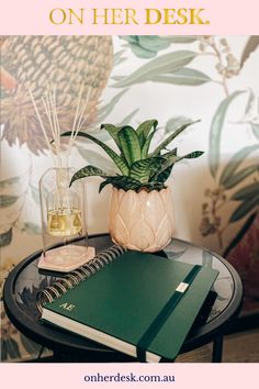 a desk with a plant and notebook on it