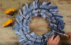 someone is making a wreath out of old jeans and some sunflowers on the table