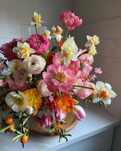 a vase filled with lots of colorful flowers on top of a white counter next to a window