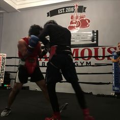 two men in the ring during a boxing match, one is wearing red and the other is black